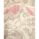 Close-up of intricately embroidered floral fabric in neutral beige.