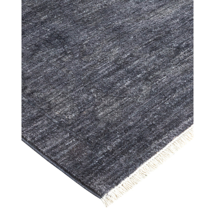 Dark, textured rug with soft pile and contrasting fringe detail.