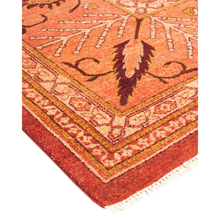 Close-up of an ornate, handcrafted rug with vibrant orange hues