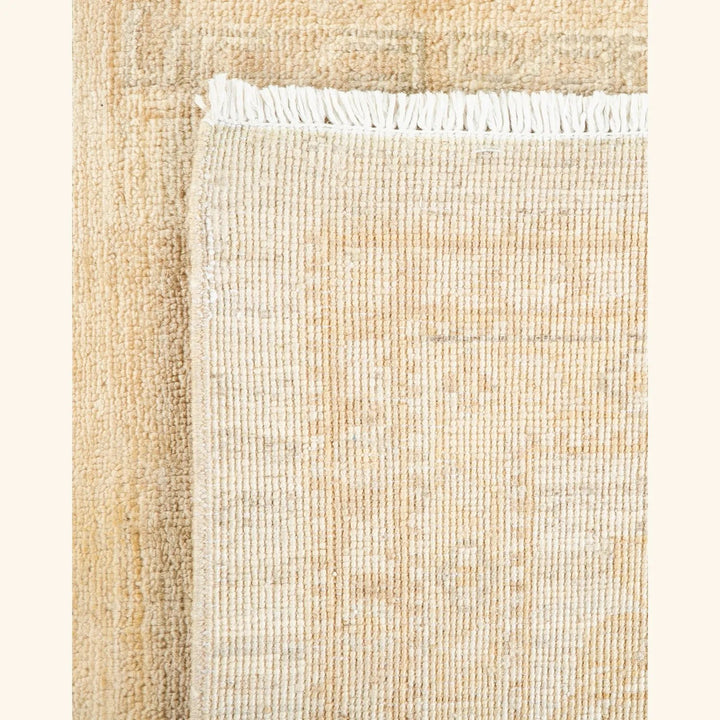 Close-up view of a neutral-toned woven textile with fringe edge.