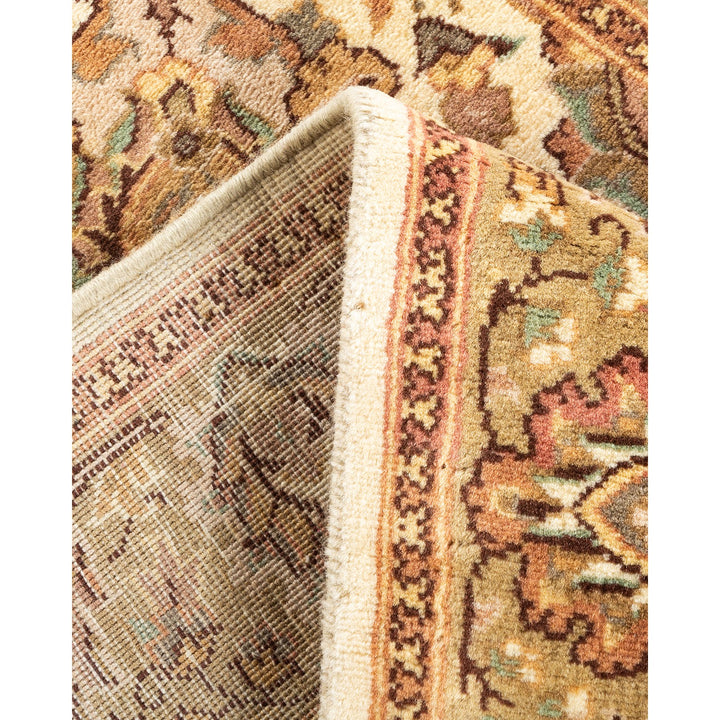 Close-up of folded carpet with intricate pattern in beige, brown, green, and rust.