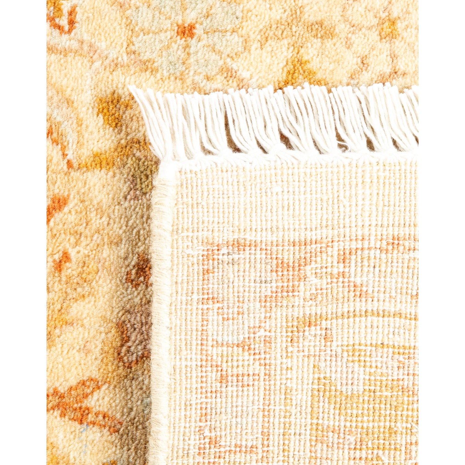 Close-up of a yellowish-cream patterned rug with fringed edge.