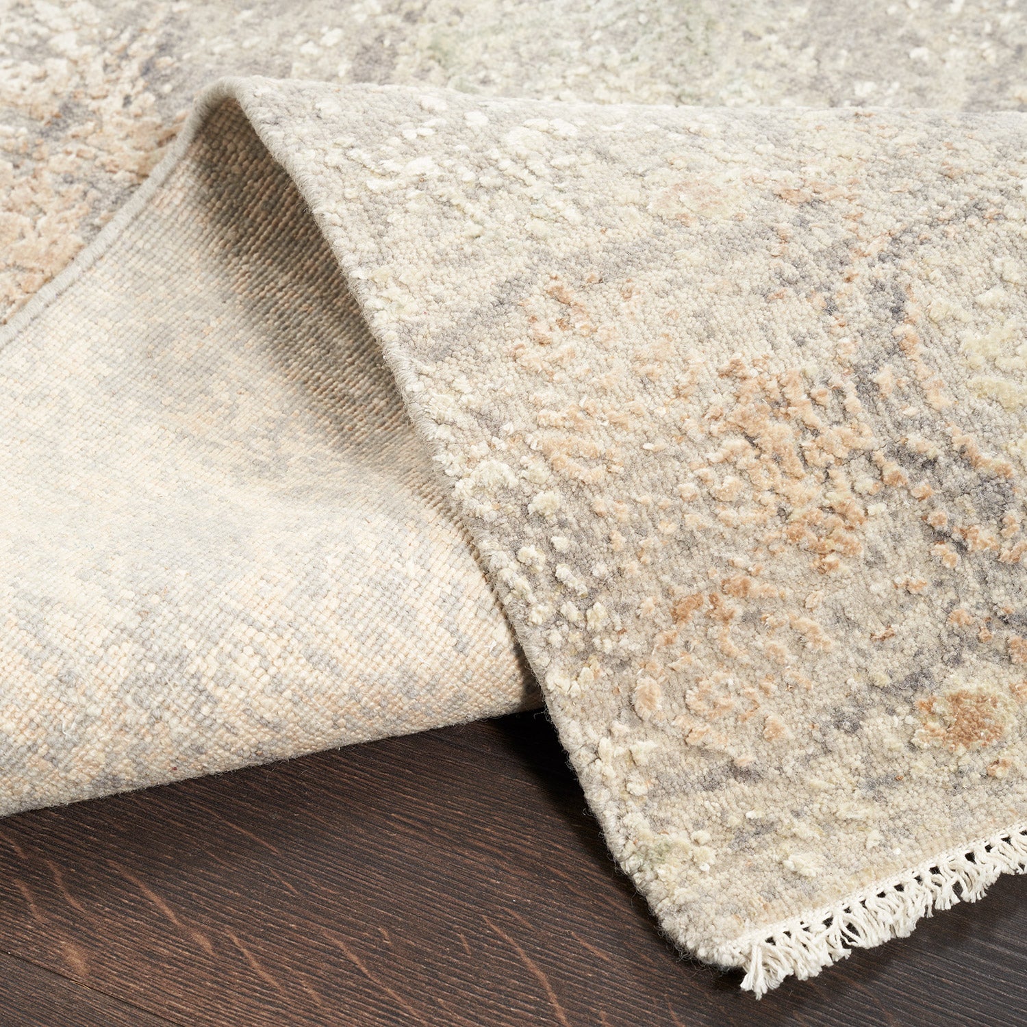 Close-up of a folded corner of plush, patterned carpet on hardwood floor.