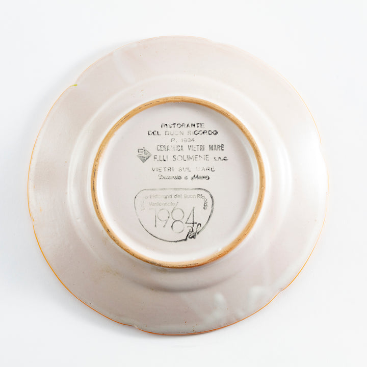 Back of a ceramic plate with inscriptions, stamps, and discoloration.