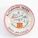 Decorative ceramic plate depicts seafood illustrations surrounding cooking pot.