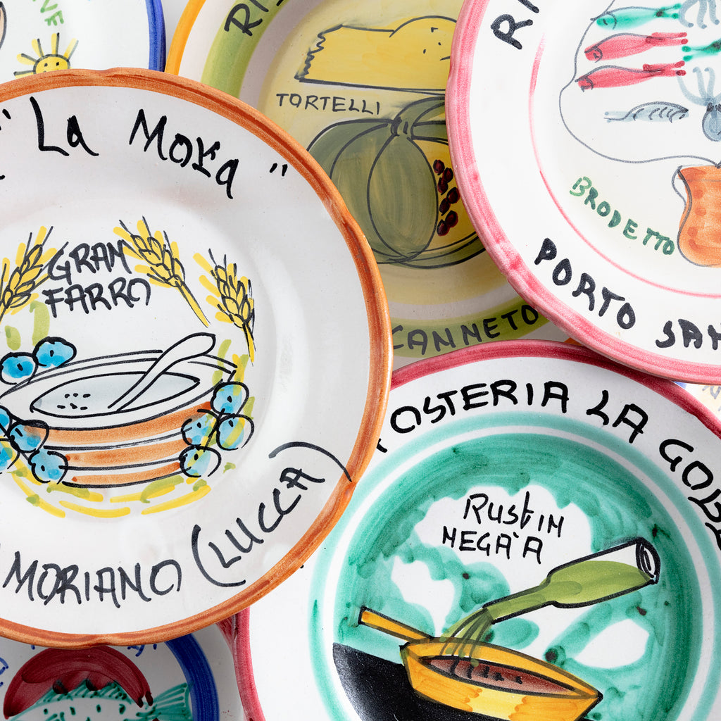 Vibrant hand-painted ceramic plates showcase Italian culinary and cultural references.