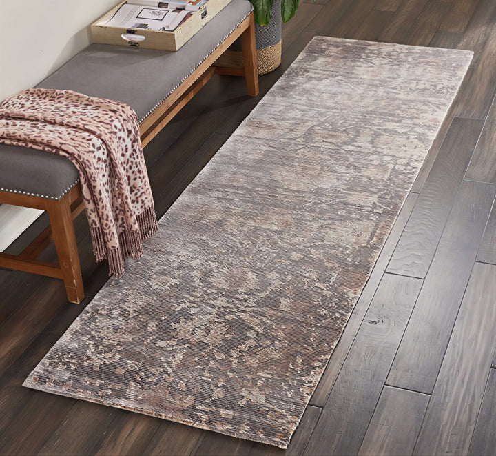 Cozy interior with weathered rug, tufted bench, and leafy plant.