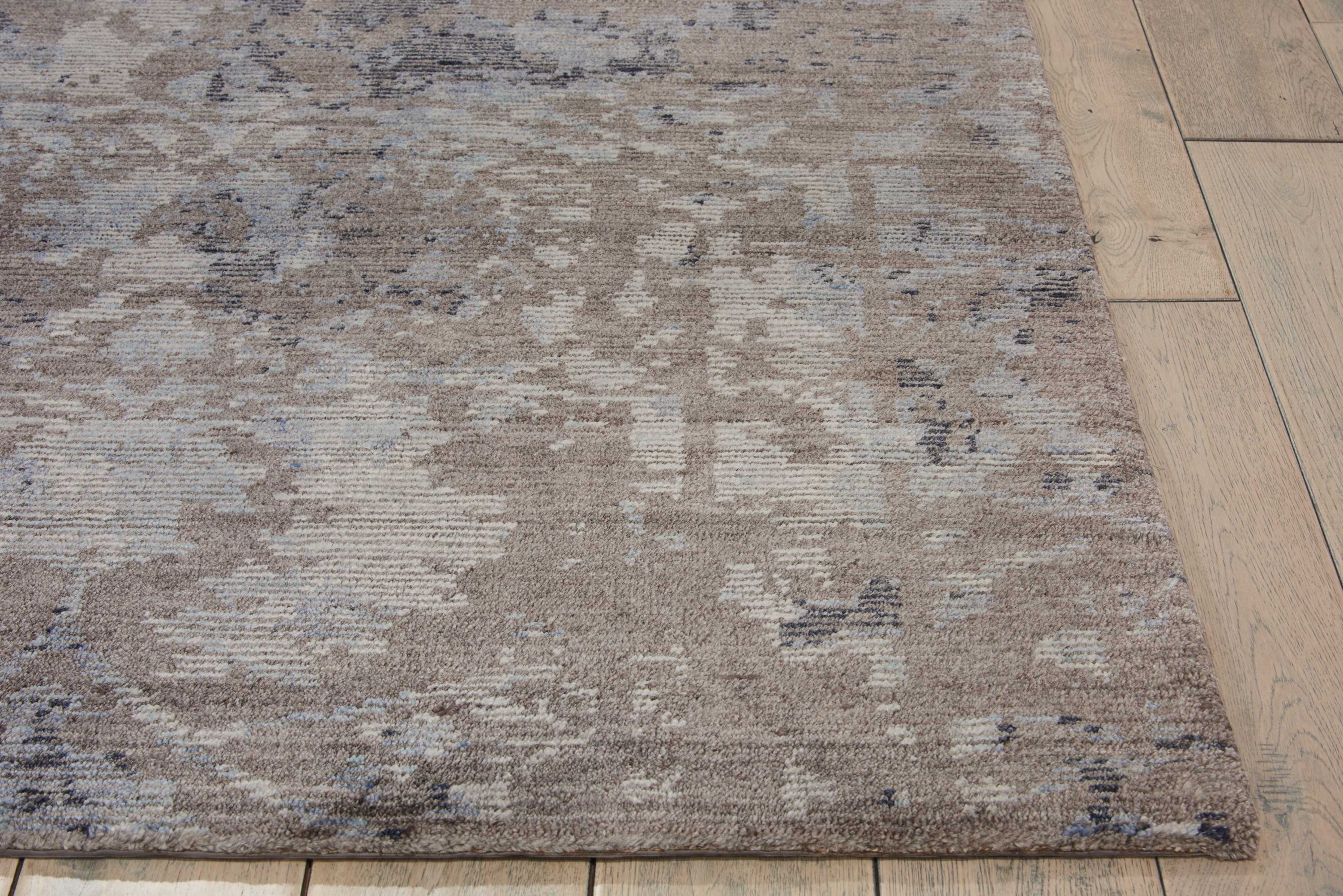Patterned area rug with distressed design on wooden floor.