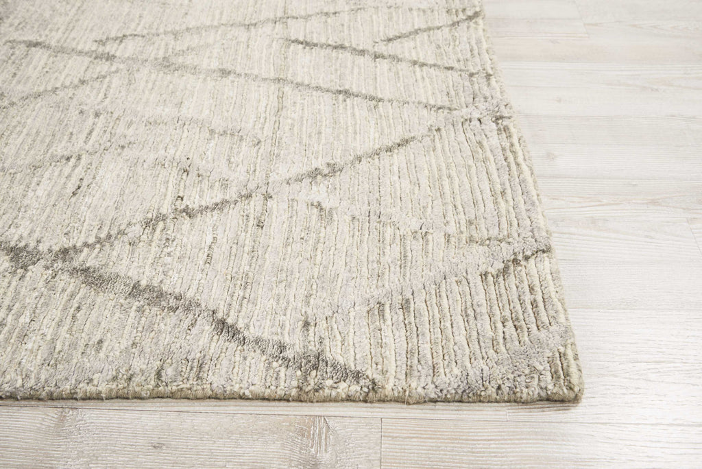 Close-up of a soft, neutral area rug on wooden floor.