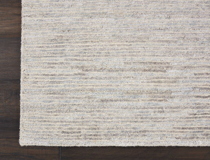 Close-up of a textured, striped rug on a wooden floor.