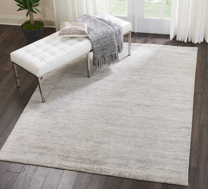 Contemporary styled room with textured rug, tufted bench, and greenery.