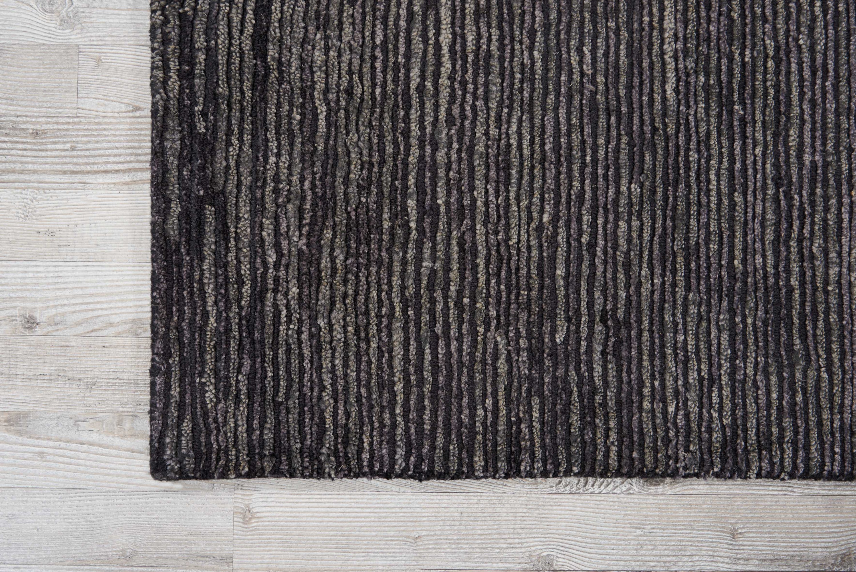 Close-up of textured area rug with striped pattern on wooden floor