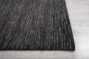 Close-up of a dark, textured rug on a wooden floor.