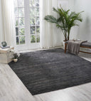 Contemporary room with dark gradient rug, light hardwood flooring, and natural accents.