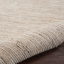 Close-up view of textured carpet with rolled edge on wooden floor.