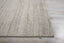 Textured area rug on wooden floor with ribbed pattern; neutral colors.