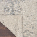 Close-up of a partially folded carpet revealing polished wooden floor.