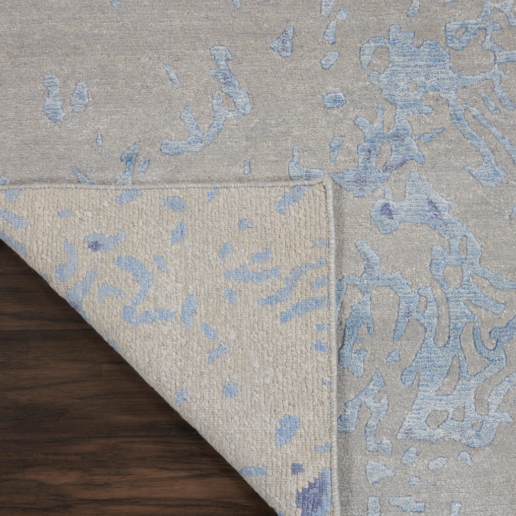 Decorative rug with abstract blue pattern laid on dark wooden floor.