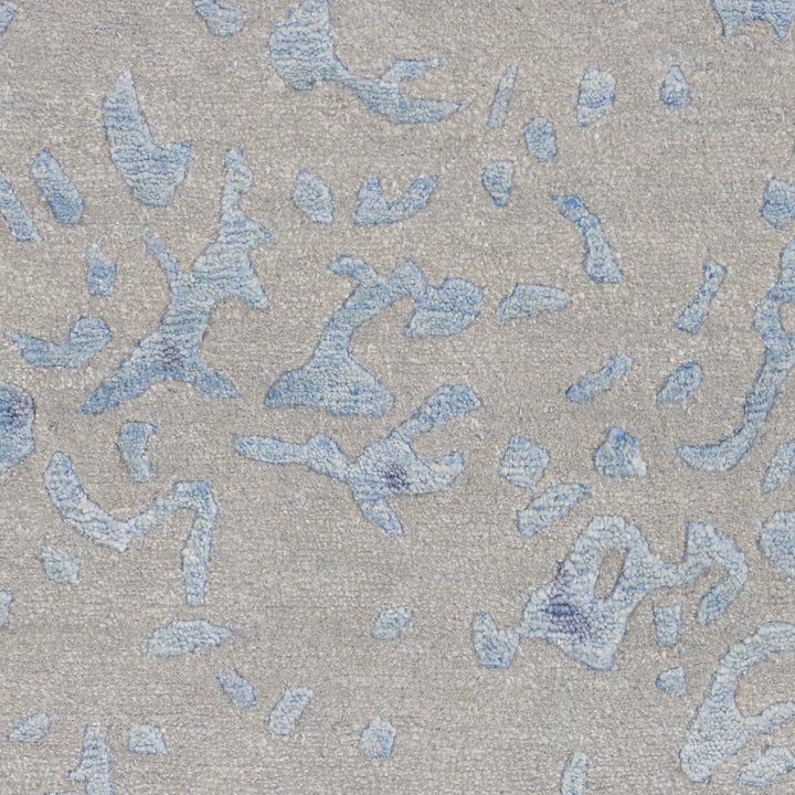 Close-up of distressed fabric with blue denim-like patches on beige background.