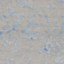 Close-up of distressed fabric with blue denim-like patches on beige background.