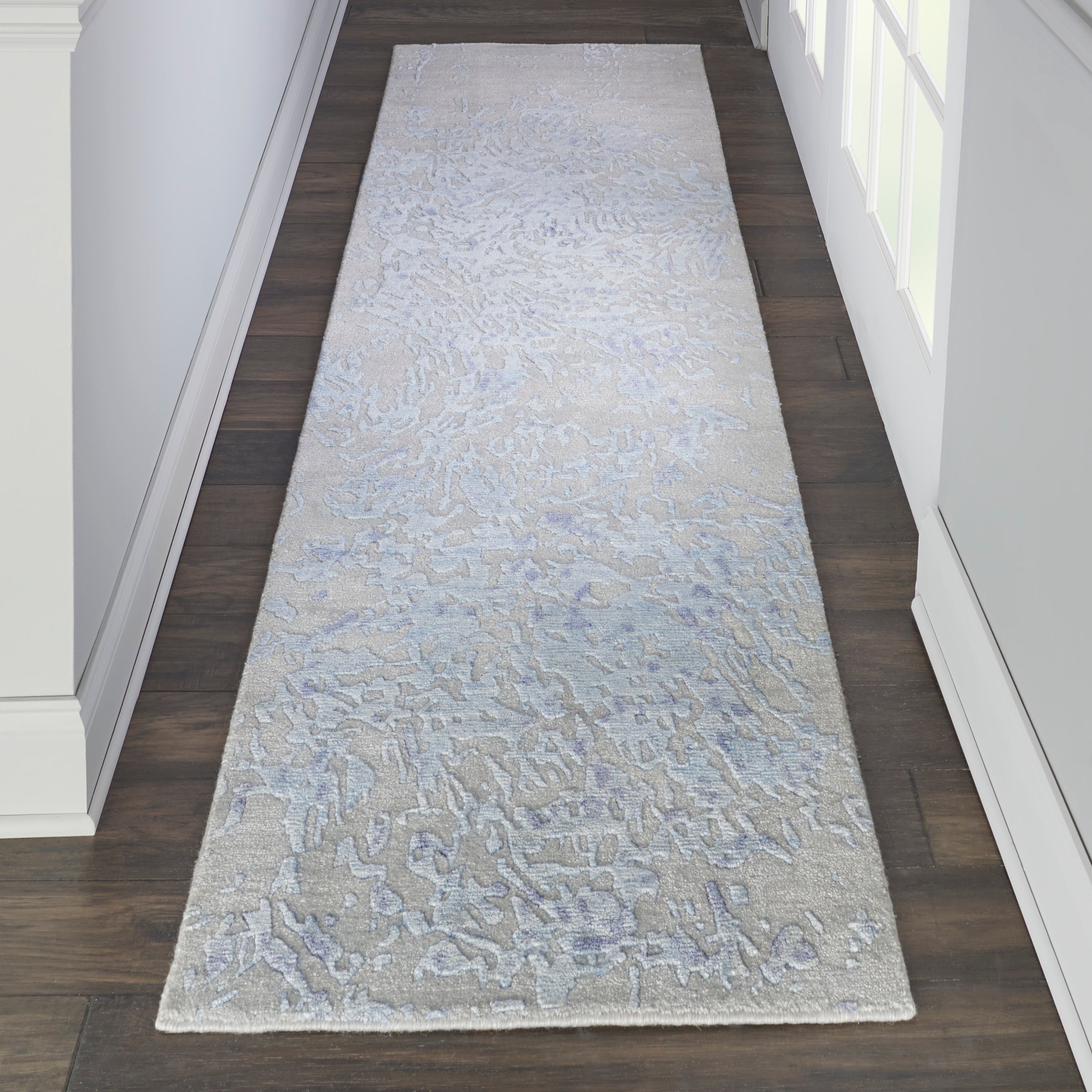 A light-colored, patterned rug lies on a dark hardwood floor.