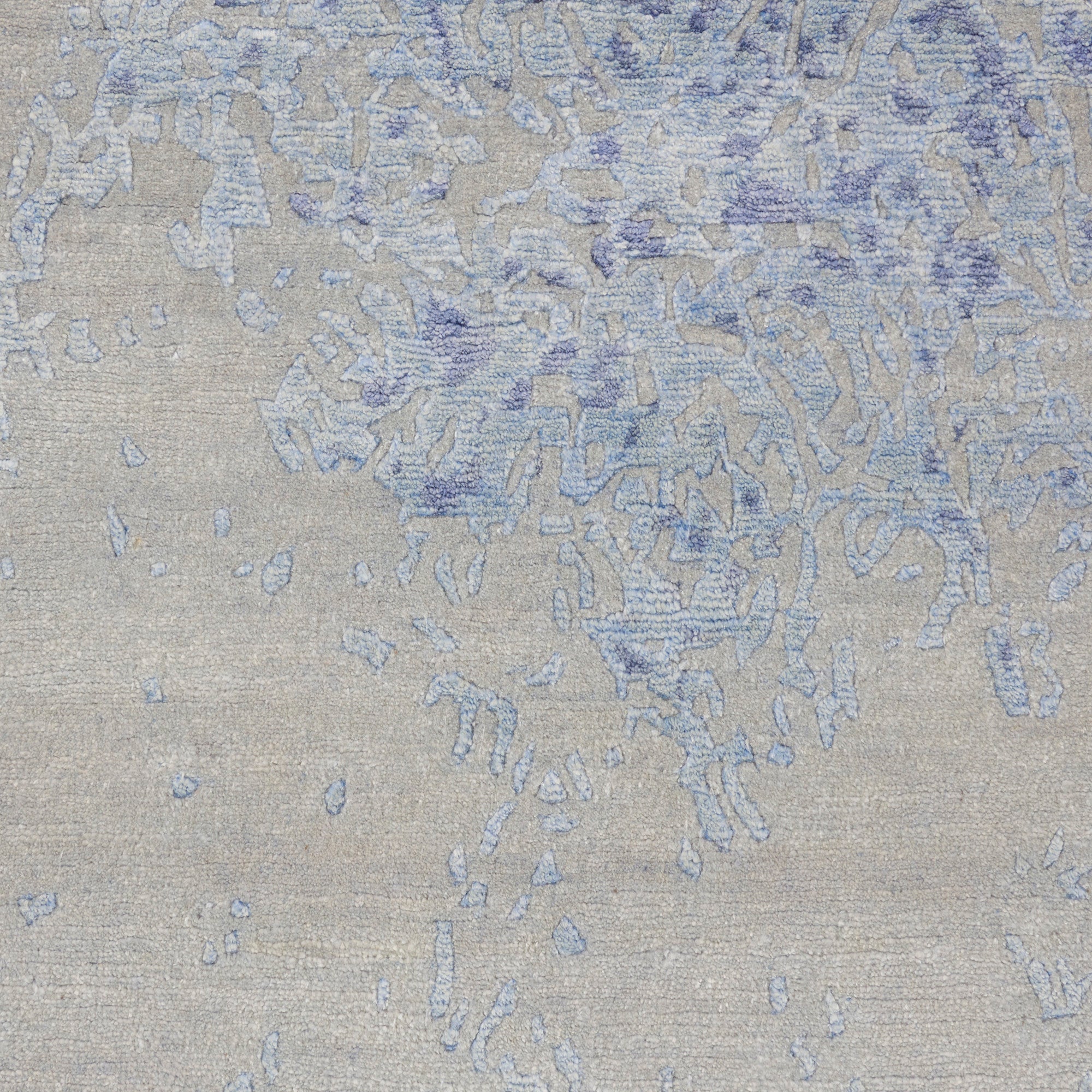 Close-up of beige denim fabric with faded blue speckles and streaks.