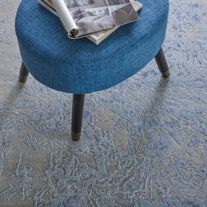 Modern round ottoman with blue upholstery on patterned carpet.