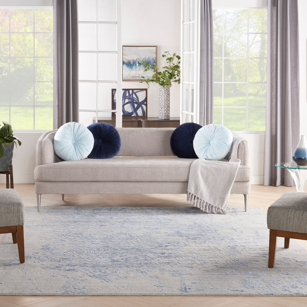 Contemporary living room with beige sofa, blue accents, and natural light.
