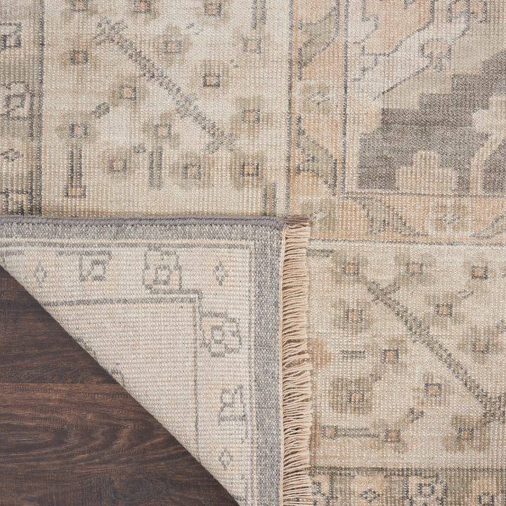 Close-up of folded patterned carpet on wooden floor, showing underside.