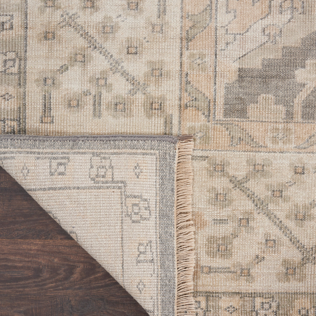 Close-up of folded patterned carpet on wooden floor, showing underside.
