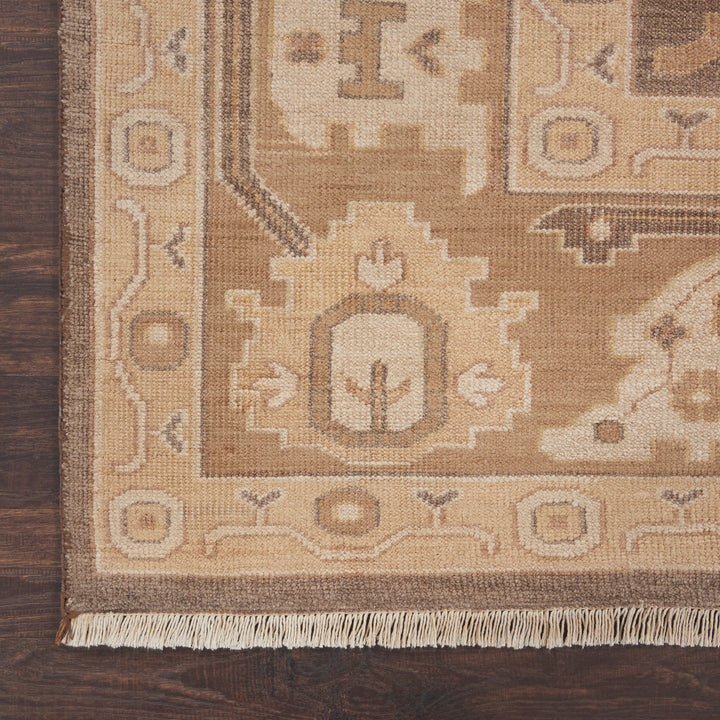 Close-up of a hand-woven rug with intricate geometric and floral design on wooden floor.