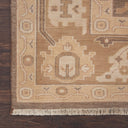 Close-up of a hand-woven rug with intricate geometric and floral design on wooden floor.