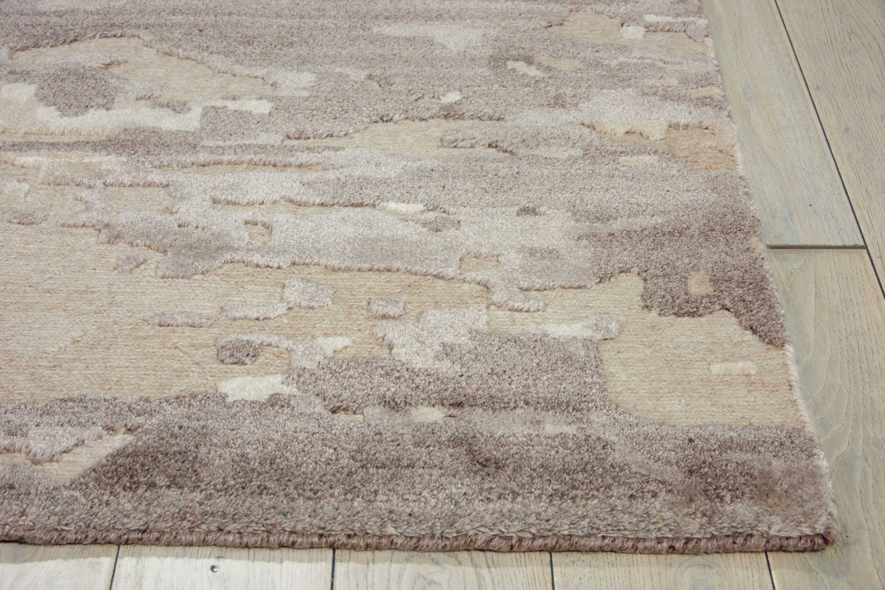 Close-up of a plush area rug with abstract beige-brown pattern.