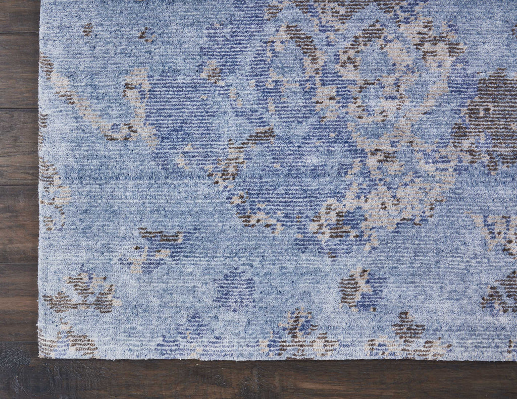 Distressed blue rug with abstract floral motif on wooden floor.