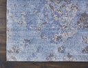 Distressed blue rug with abstract floral motif on wooden floor.
