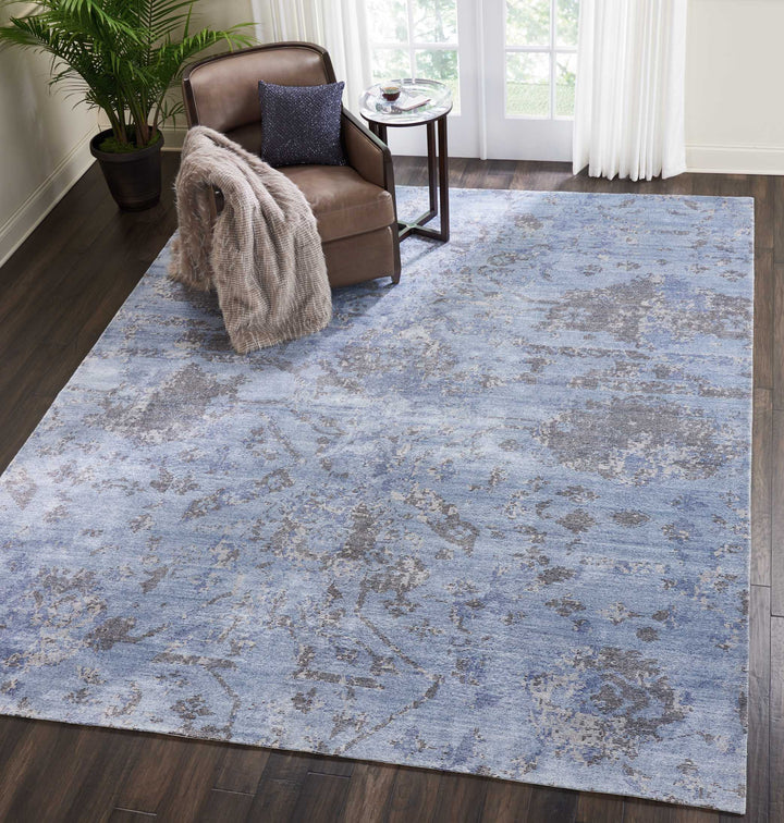 Cozy, modern room with hardwood floors, distressed area rug, and leather armchair.