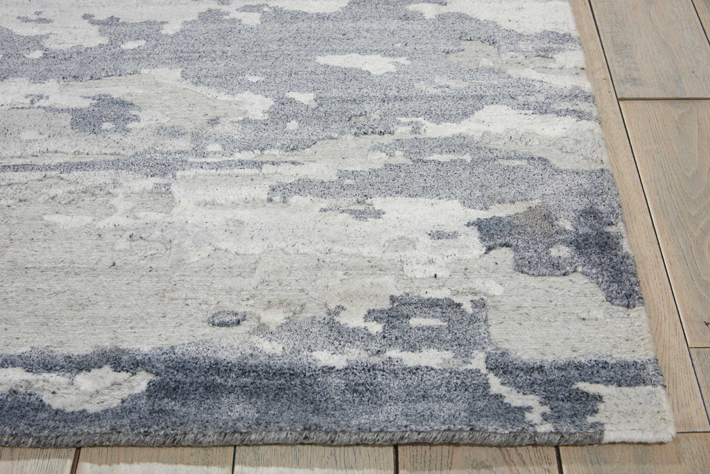 Close-up of a distressed, abstract patterned rug on wooden floor.