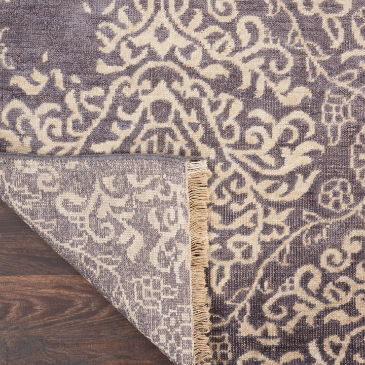 Intricate traditional rug with detailed patterns and slightly worn fringe.