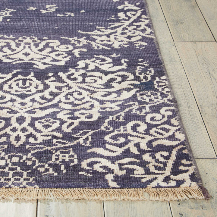 Elegant white rug with intricate floral patterns on dark background.