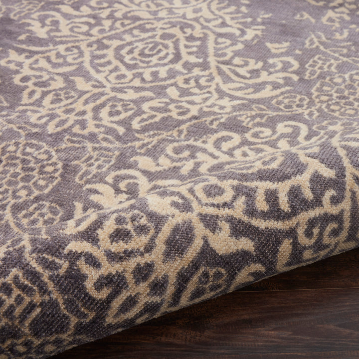 Close-up of a ornate patterned rug on a wooden floor.