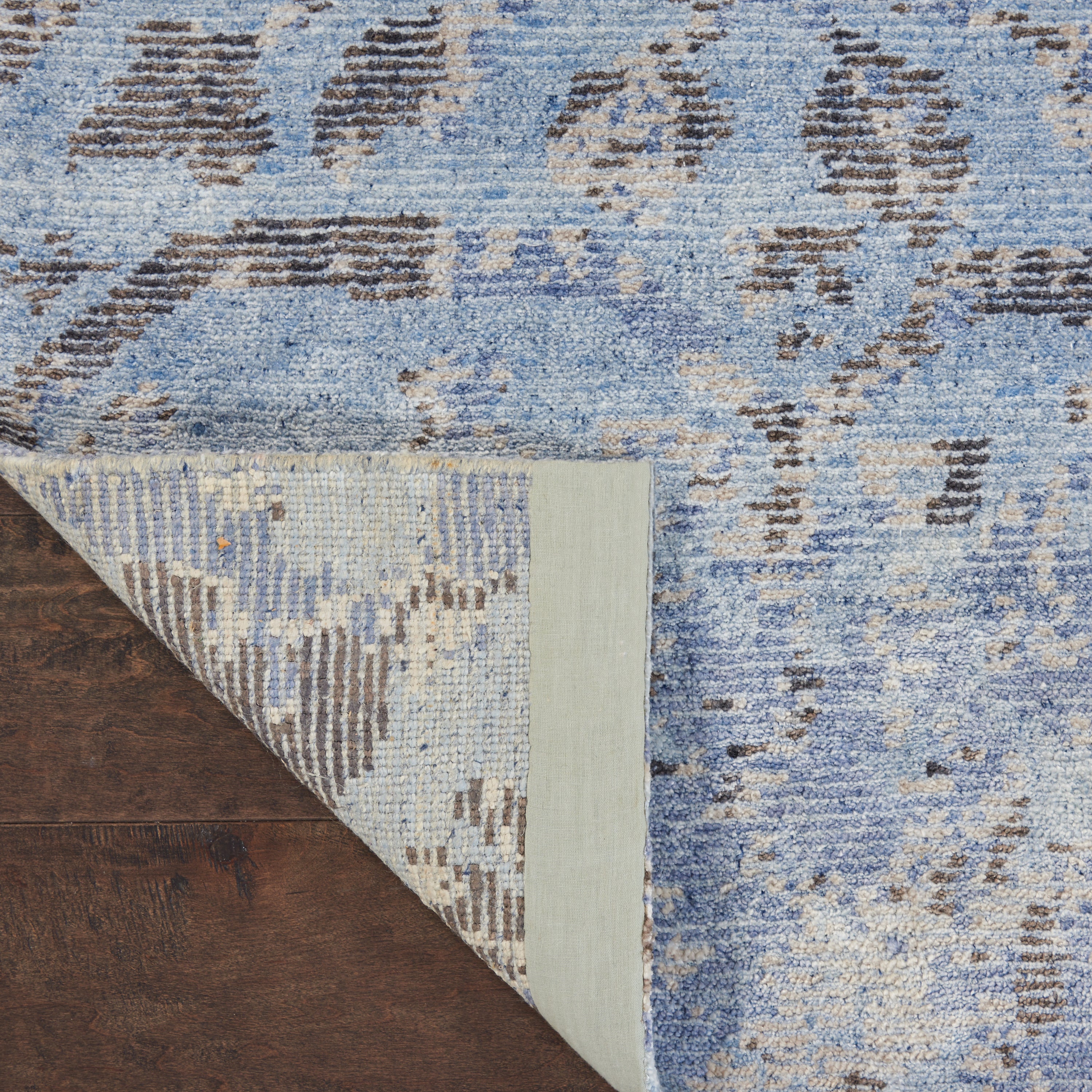 Close-up of a blue textile area rug with abstract pattern.