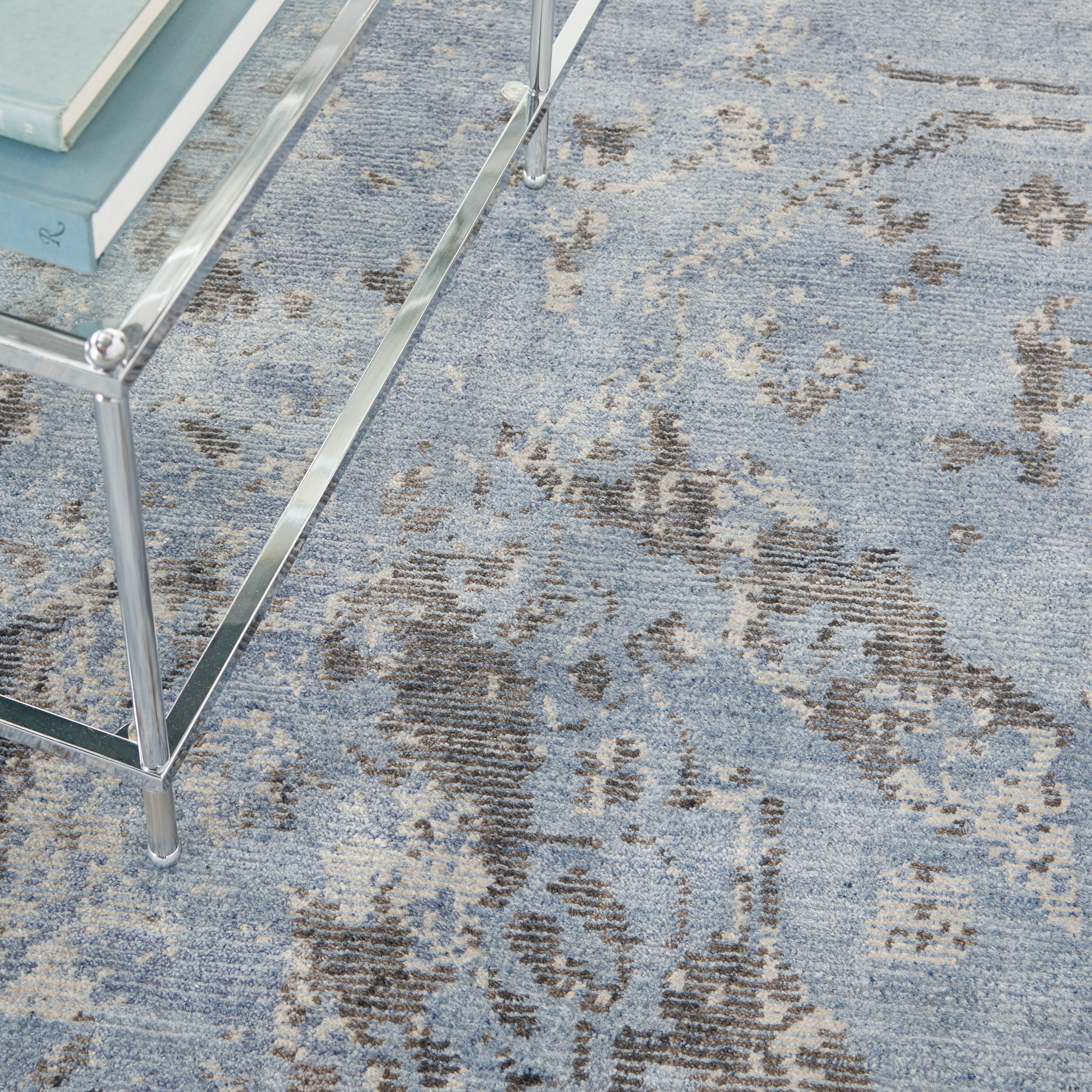 Close-up of a predominantly blue distressed patterned carpet with furniture leg.