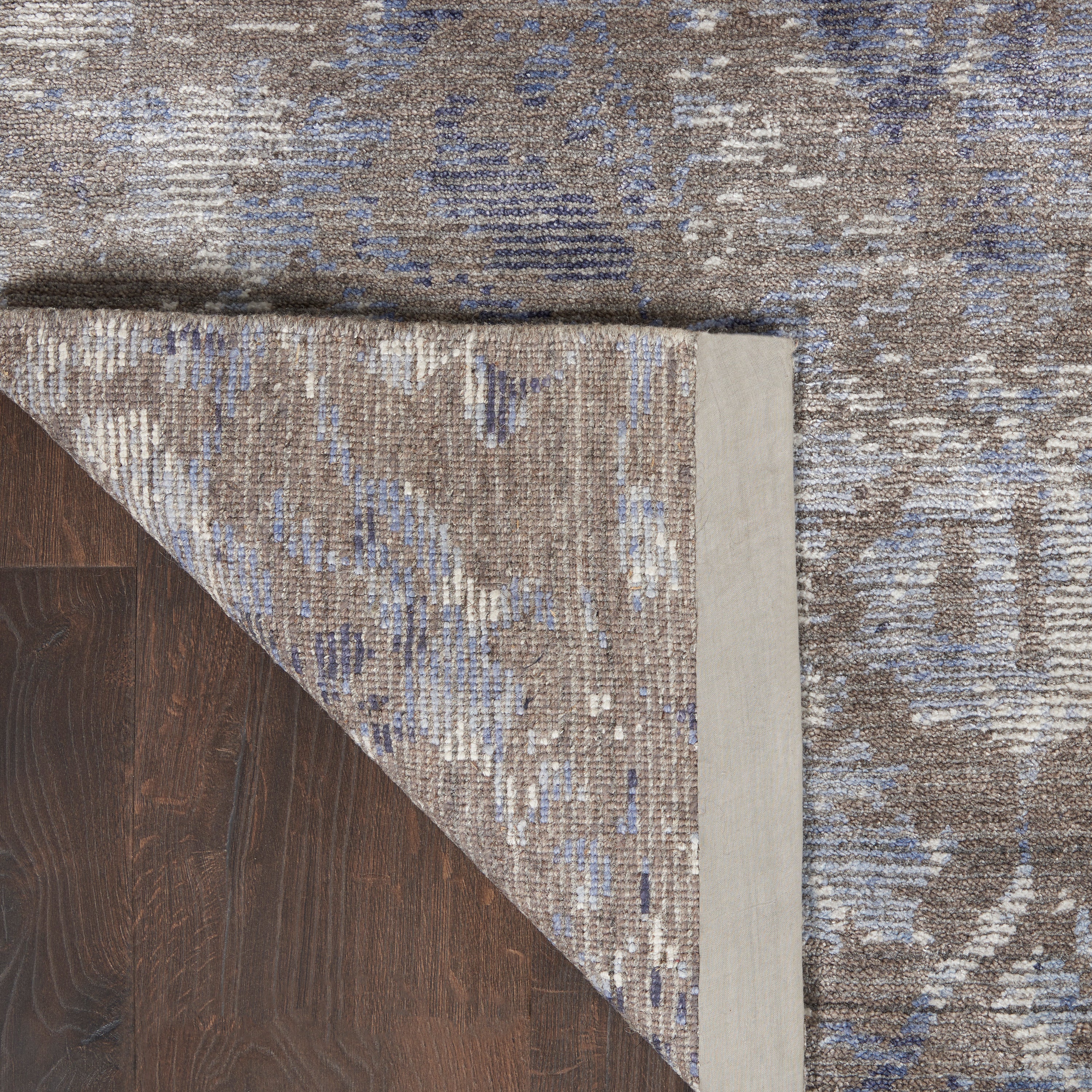 Close-up of a wood floor and abstract patterned rug corner.