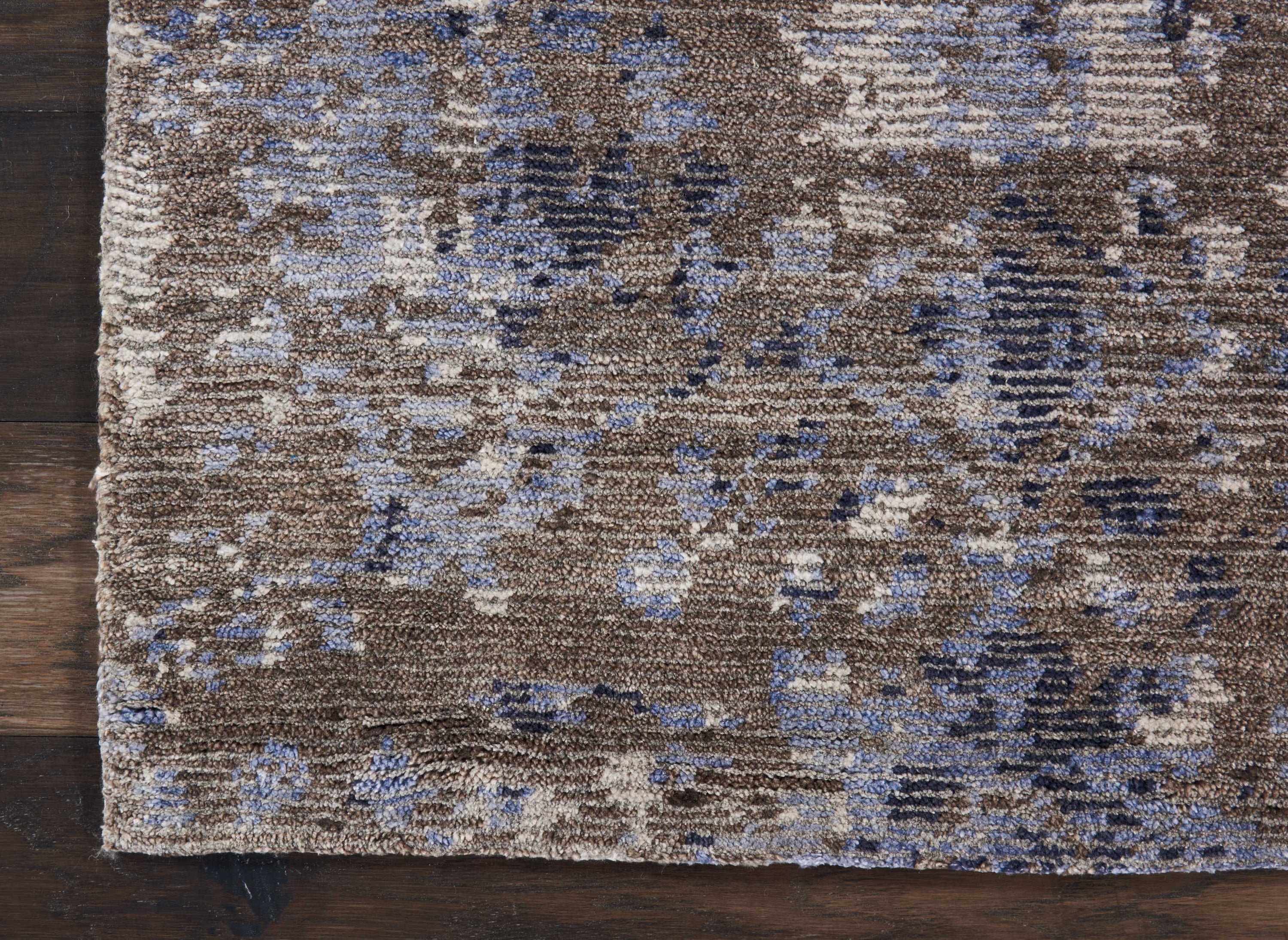 Close-up view of a textured area rug on a wooden floor.