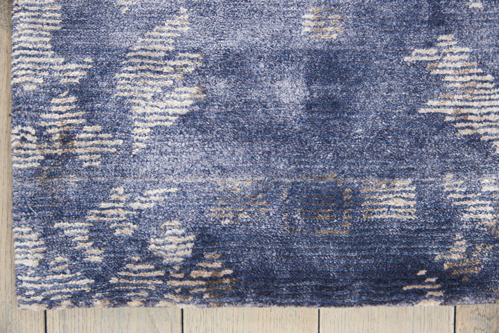 Close-up of distressed blue patterned carpet contrasts with hardwood floor.