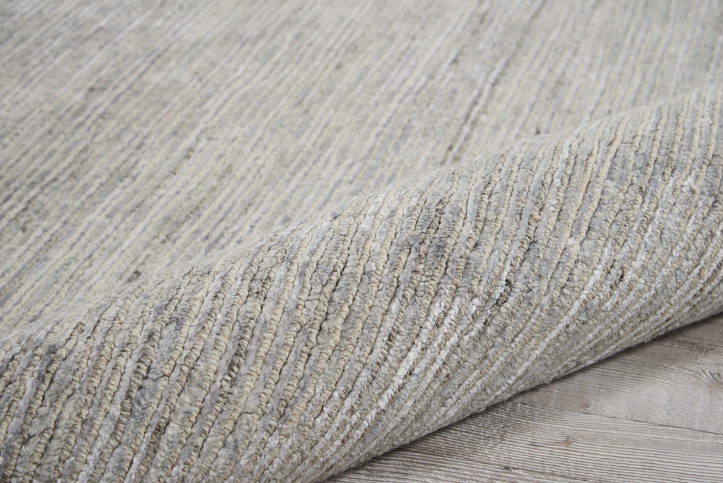 Close-up of a durable, neutral-toned woven carpet partially rolled up.