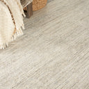 Close-up view of textured floor covering with fringe edge and woven basket, creating a warm and cozy domestic space.