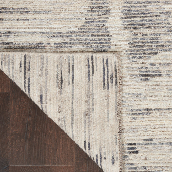 Textured, patterned rug with dark blue stripes complements wooden floor.