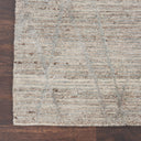 Close-up of a high-quality textured rug on a hardwood floor.