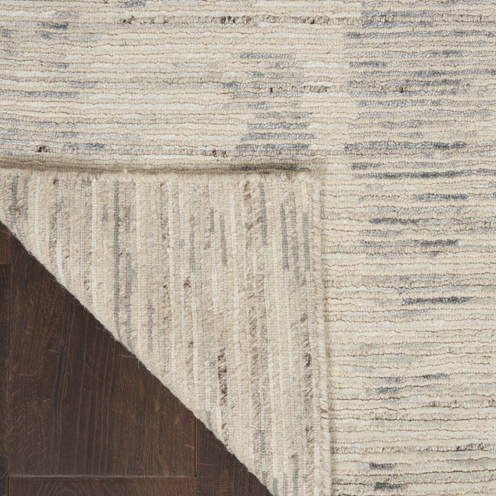Close-up view of textured area rug overlaid on hardwood floor.